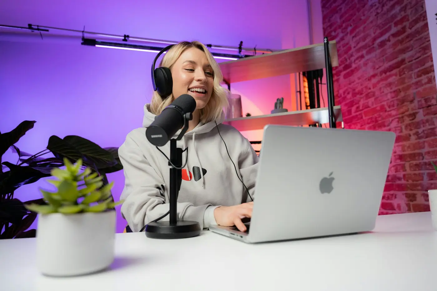 A creator recording at a desk with a laptop and microphone
