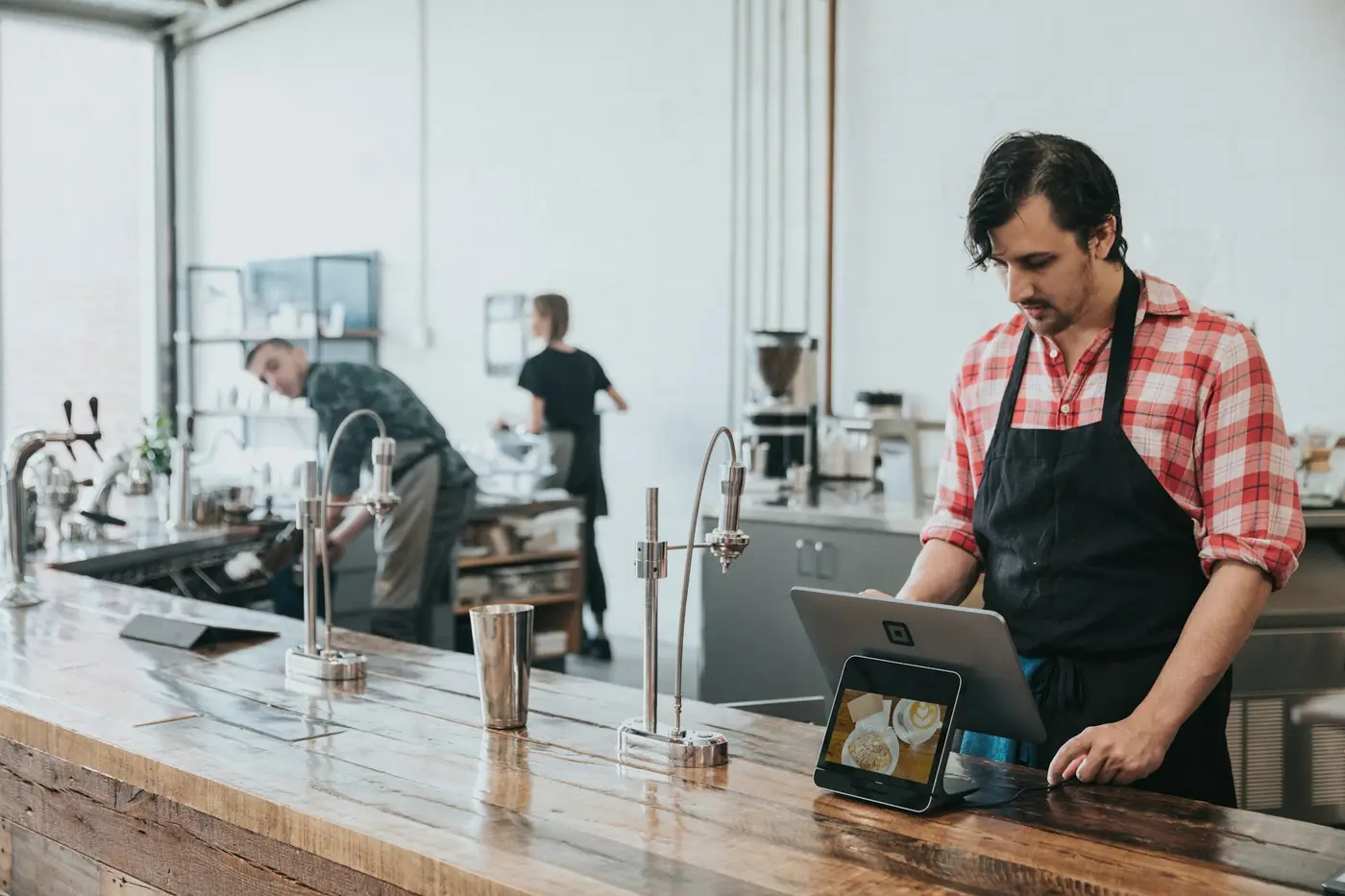 Café owner taking a payment on a tablet at the counter