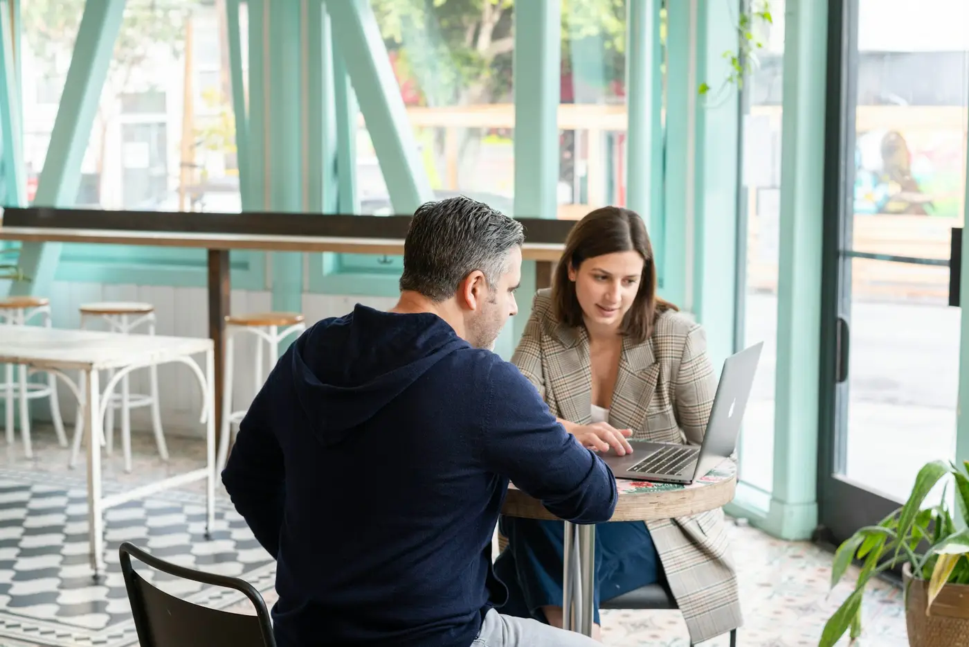 An adviser going through a laptop with a business owner in a café